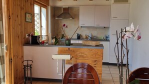 Een keuken met houten kastjes, een centraal eiland en een zithoek met twee stoelen.