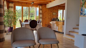 Een houten interieur met een eethoek, stoelen, een tafel en uitzicht op het buitengebied.