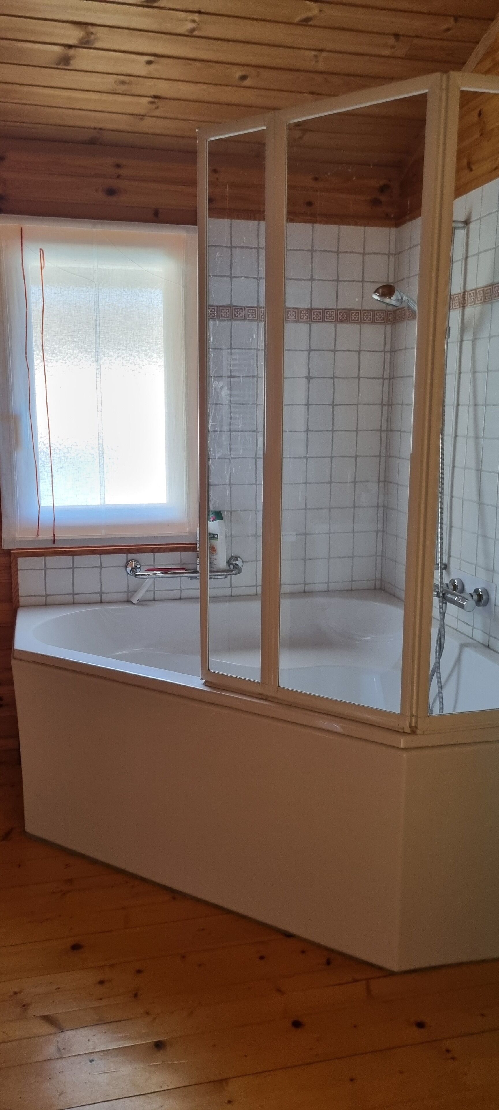 A bathroom with a bathtub, shower, and window.