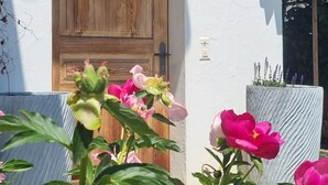Een gebouw met een houten deur en een hartvormig uitsparing, omgeven door levendige roze bloemen.