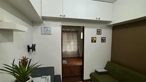 Um espaço compacto com cozinha compacta, um sofá verde, uma mesa pequena e um vaso com planta.