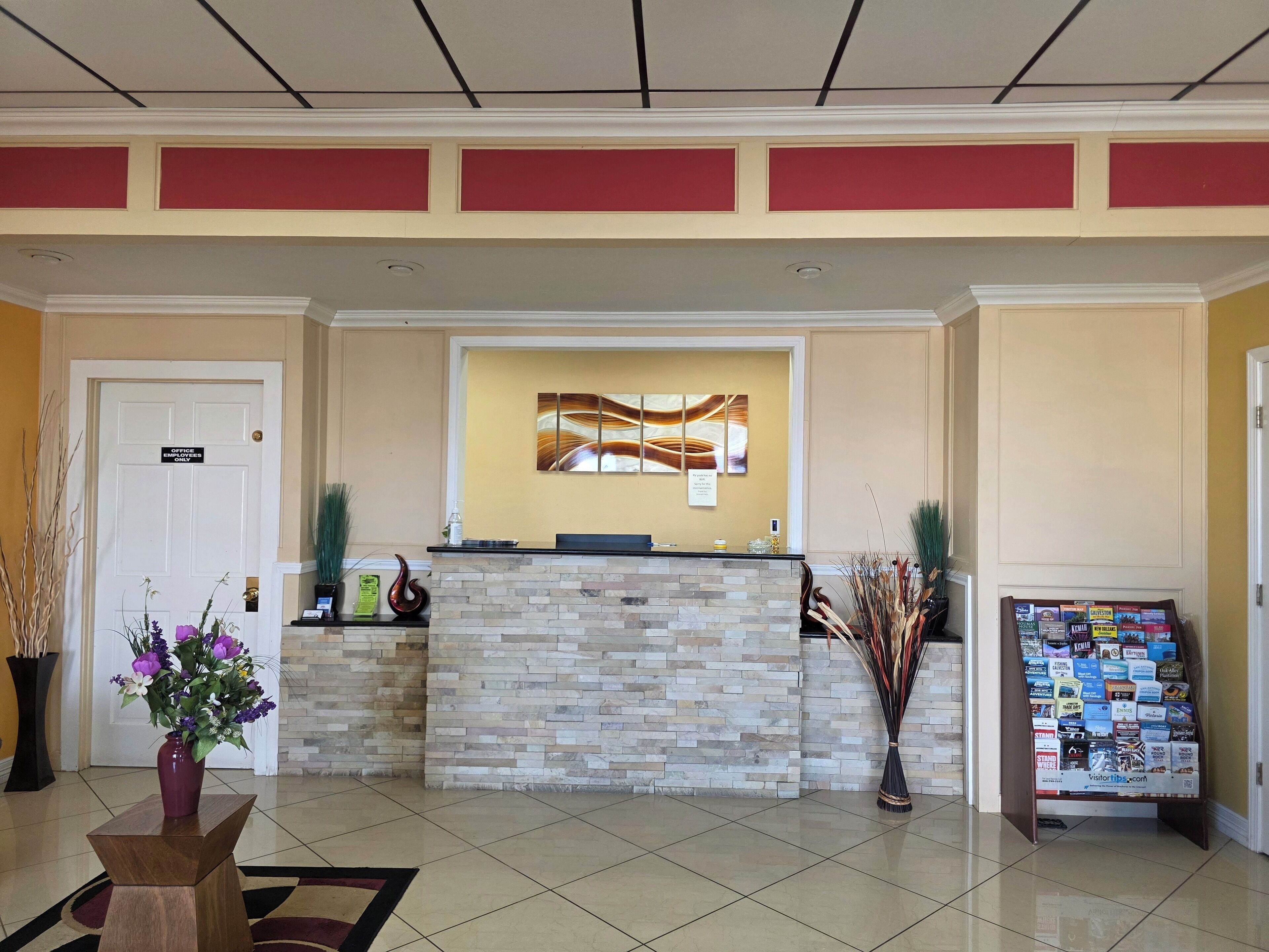 A reception area with a stone counter, a wall-mounted artwork, a sign indicating 'Office Use Only,' and a stand with brochures.