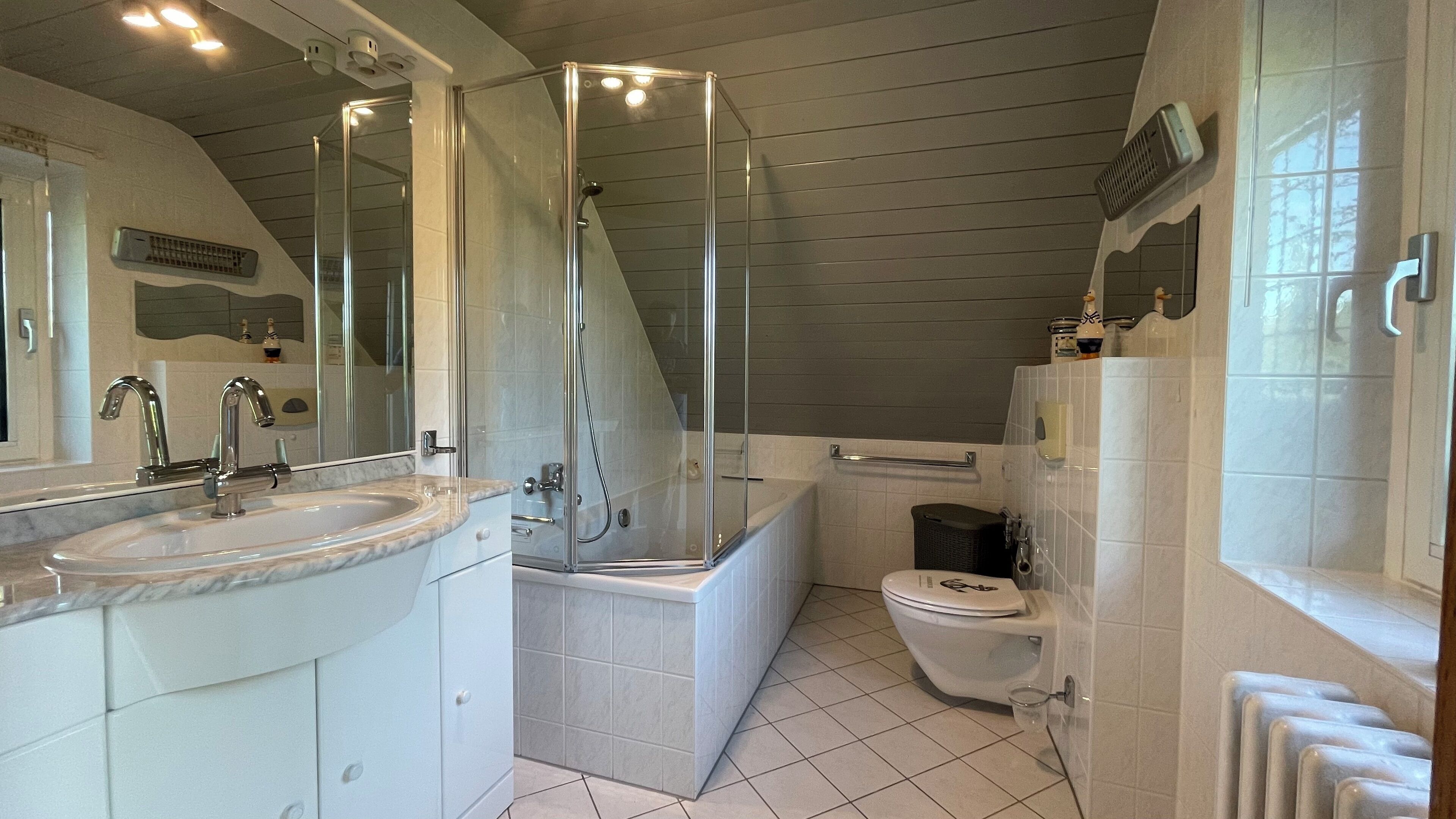 Et badeværelse med bruseniche, et hvidt håndvask og et toilet.