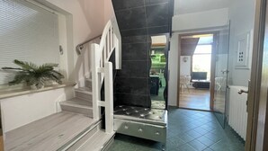 A staircase with a white railing leading to a room with a dark tiled wall and a green floor. - Vacation home-Nature-Elbe-View-Fully equipped (Magdeburg)