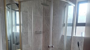 A bathroom with a glass-enclosed shower, a white sink, and a toilet.