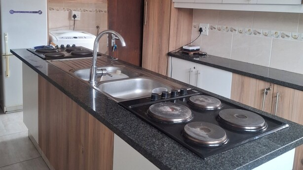 A kitchen with a central island, a built-in stove, a sink, and wooden cabinets.