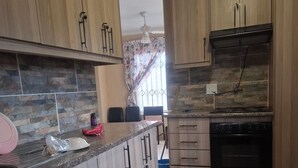 A kitchen with wooden cabinets, a granite countertop, a built-in oven, and a tiled backsplash.