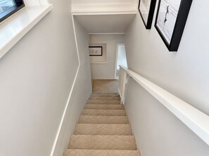 A staircase with a white handrail, carpeted steps, and framed pictures on the walls. - Shoreline Retreat - beach frontage - 2 King Beds (Scarborough)