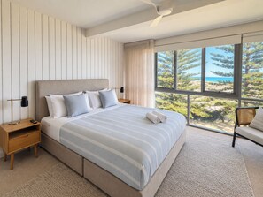 A modern hotel room with a large bed, a nightstand, a lamp, and a view of the outdoors. - Shoreline Retreat - beach frontage - 2 King Beds (Scarborough)