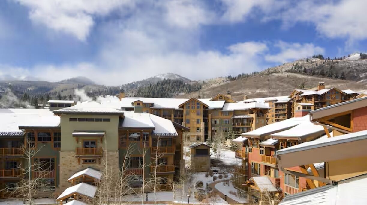 Un resort con varias edificaciones, techos cubiertos de nieve y montañas al fondo.