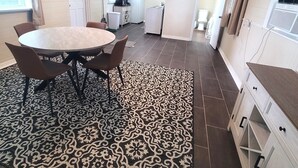 Une cuisine de taille réduite avec un coin repas, un tapis à motifs et un petit réfrigérateur.