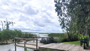 Une jetée en bois s’étendant au-dessus d’une étendue d’eau, entourée d’une végétation luxuriante et d’arbres.