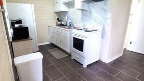 Une cuisine de taille réduite avec des meubles blancs, une cuisinière et un évier.