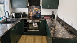 A modern kitchen with dark green cabinets, a marble countertop, and a central island. - Hetton Modern Stay near Durham (Hetton-le-Hole)