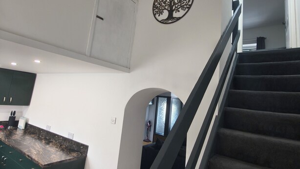 A modern kitchen with dark cabinetry, a marble countertop, and a decorative tree wall art piece. - Hetton Modern Stay near Durham (Hetton-le-Hole)