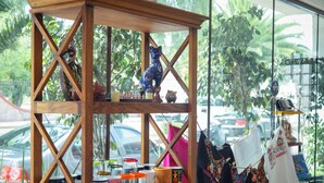 Una estantería de madera con diversos objetos, entre ellos frascos, una figurita de gato y ropa colgada.