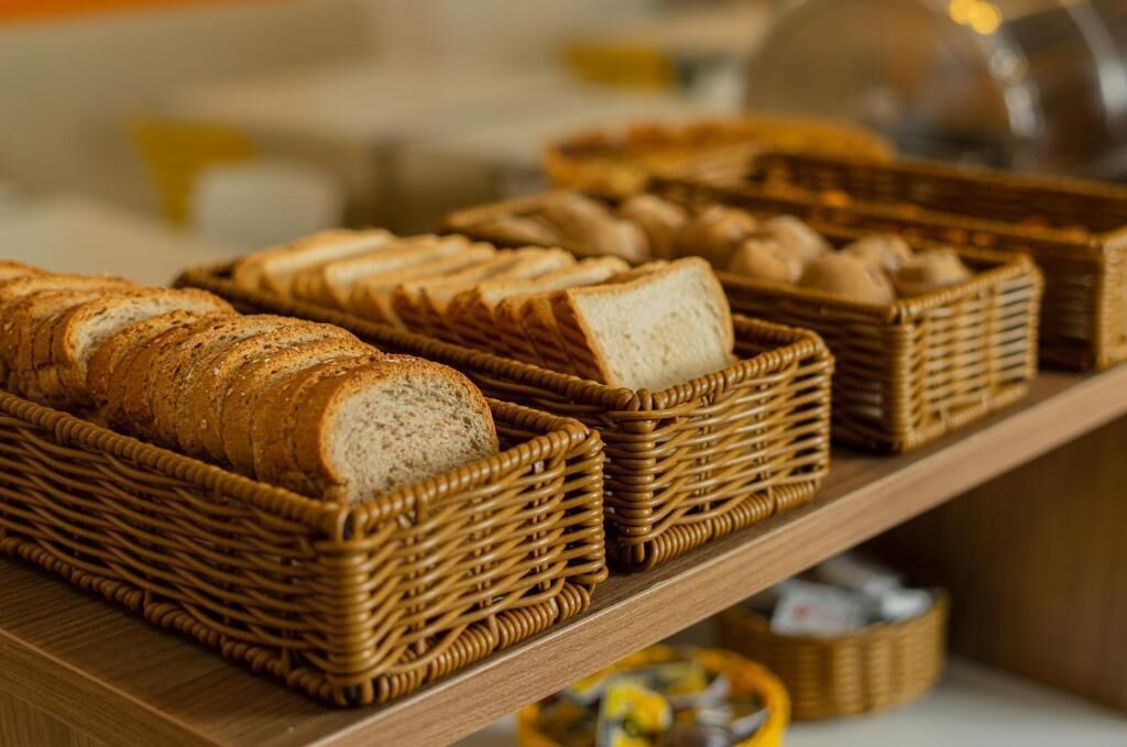 Un'esposizione di diversi pani e pasticcini in cesti di vimini su un ripiano di legno.