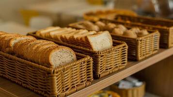 Un'esposizione di diversi pani e pasticcini in cesti di vimini su un ripiano di legno.