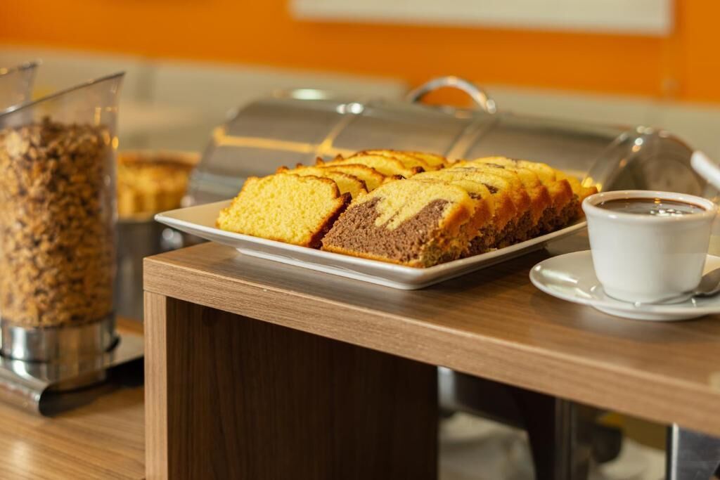 A breakfast buffet with a cake and coffee on a wooden table.