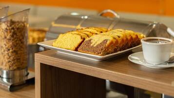 Un bufé de desayuno con pastel y café sobre una mesa de madera.
