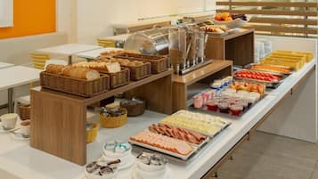 Un buffet proposant une variété de plats, notamment du pain, de la viande et des fruits.
