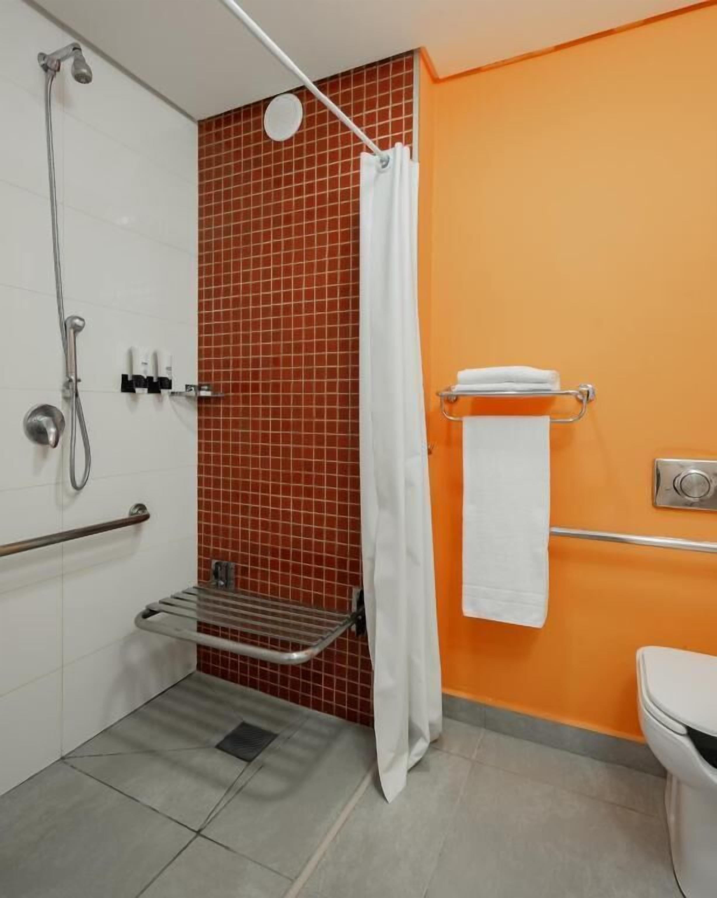 Um banheiro com chuveiro, vaso sanitário e porta-toalhas.