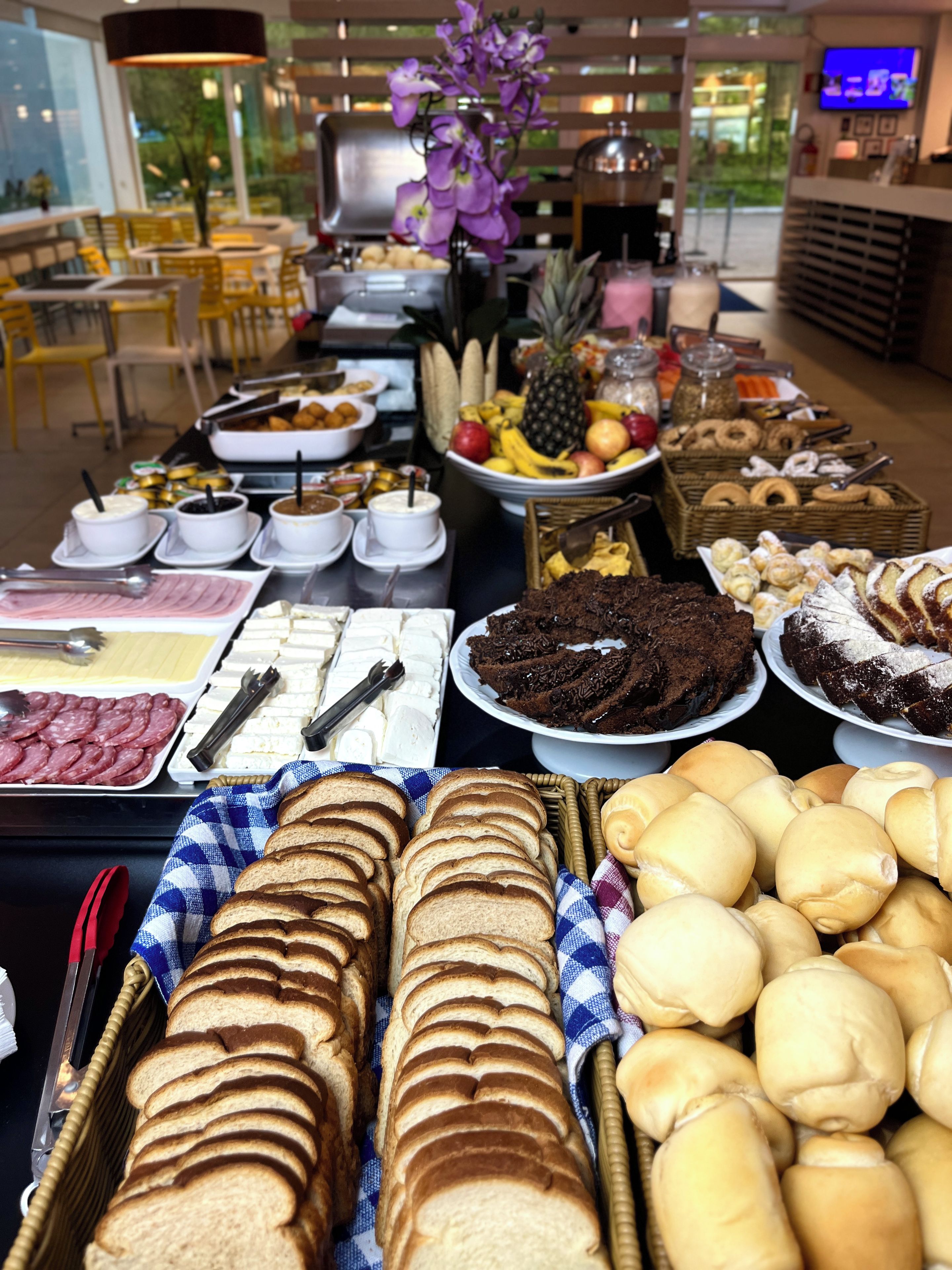 Un buffet proposant une variété de plats, notamment du pain, des pâtisseries et des fruits.