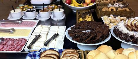 Un bufé con diversas opciones de comida, incluyendo pan, bollería y frutas.
