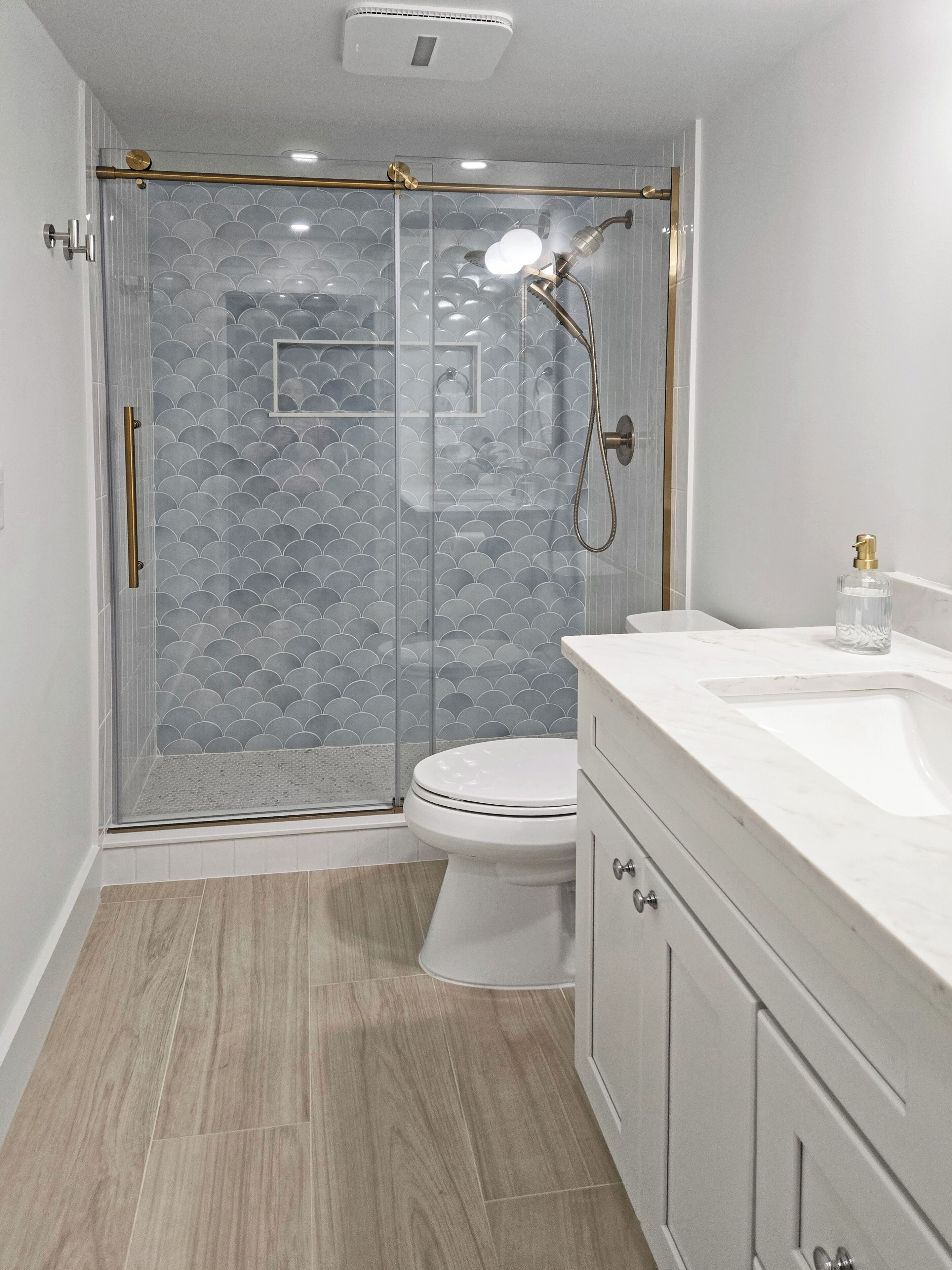 A modern bathroom with a glass-enclosed shower, a white toilet, and a marble vanity.