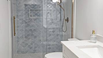 A modern bathroom with a glass-enclosed shower, a white toilet, and a marble vanity.