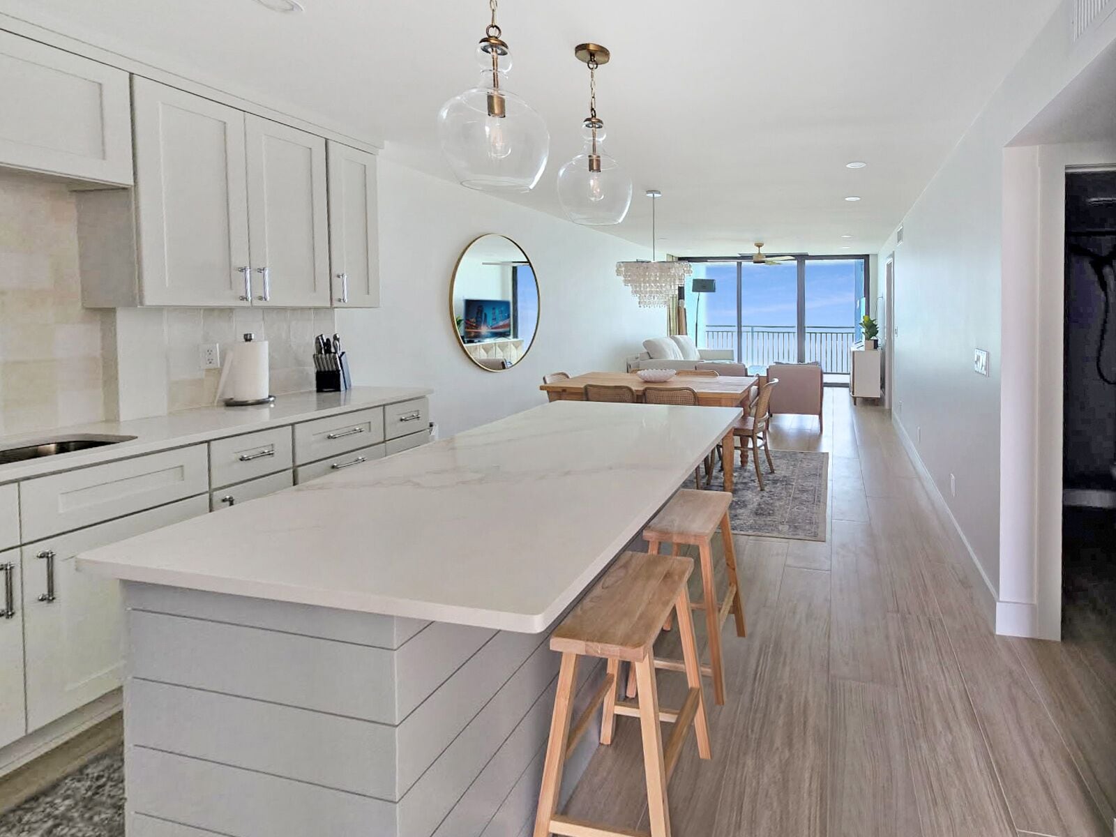 A modern kitchen with a central island, white cabinetry, and pendant lighting.