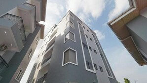 A multi-story building with a modern architectural design, featuring geometric window shapes and a neutral color palette.