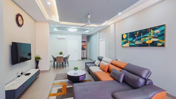 A modern living room with a sofa, TV, and artwork on the wall.