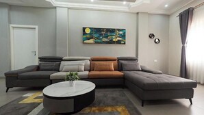 A modern living room with a sectional sofa, a round coffee table, and a large painting on the wall.