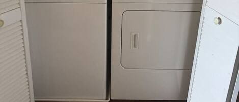 A laundry room with two front-loading washing machines and a dryer.