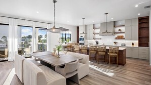 A modern kitchen with a dining area, large windows, and a view of the outdoors. - Lazy River! Mini Golf! Sleeps 16 Anna Maria Island - Nautical Situation (Anna Maria)