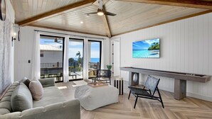 A spacious living area with a high ceiling, a large TV mounted on the wall, a wooden bench, and a sofa. - Lazy River! Mini Golf! Sleeps 16 Anna Maria Island - Nautical Situation (Anna Maria)