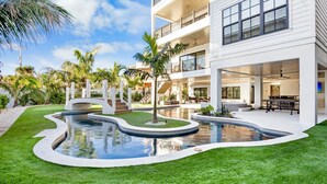 A modern multi-story building with a pool, outdoor seating, and palm trees. - Lazy River! Mini Golf! Sleeps 16 Anna Maria Island - Nautical Situation (Anna Maria)