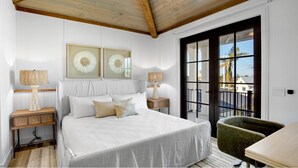 A bedroom with a large bed, two bedside lamps, a green chair, and a view of the outside through a glass door. - Lazy River! Mini Golf! Sleeps 16 Anna Maria Island - Nautical Situation (Anna Maria)