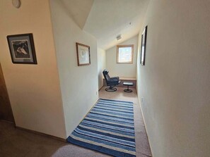 A narrow hallway with a blue striped rug leading to a small room with a chair and a table. - 2 bedroom with loft in beautiful Silverthorne! (Silverthorne)
