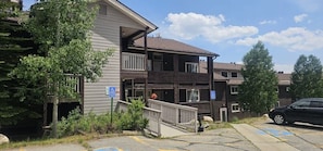 A two-story building with a balcony on the second floor. There are parking spaces in front of the building.