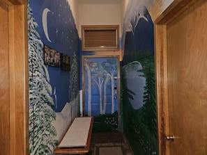 A narrow hallway with a mural of a snowy landscape and trees.