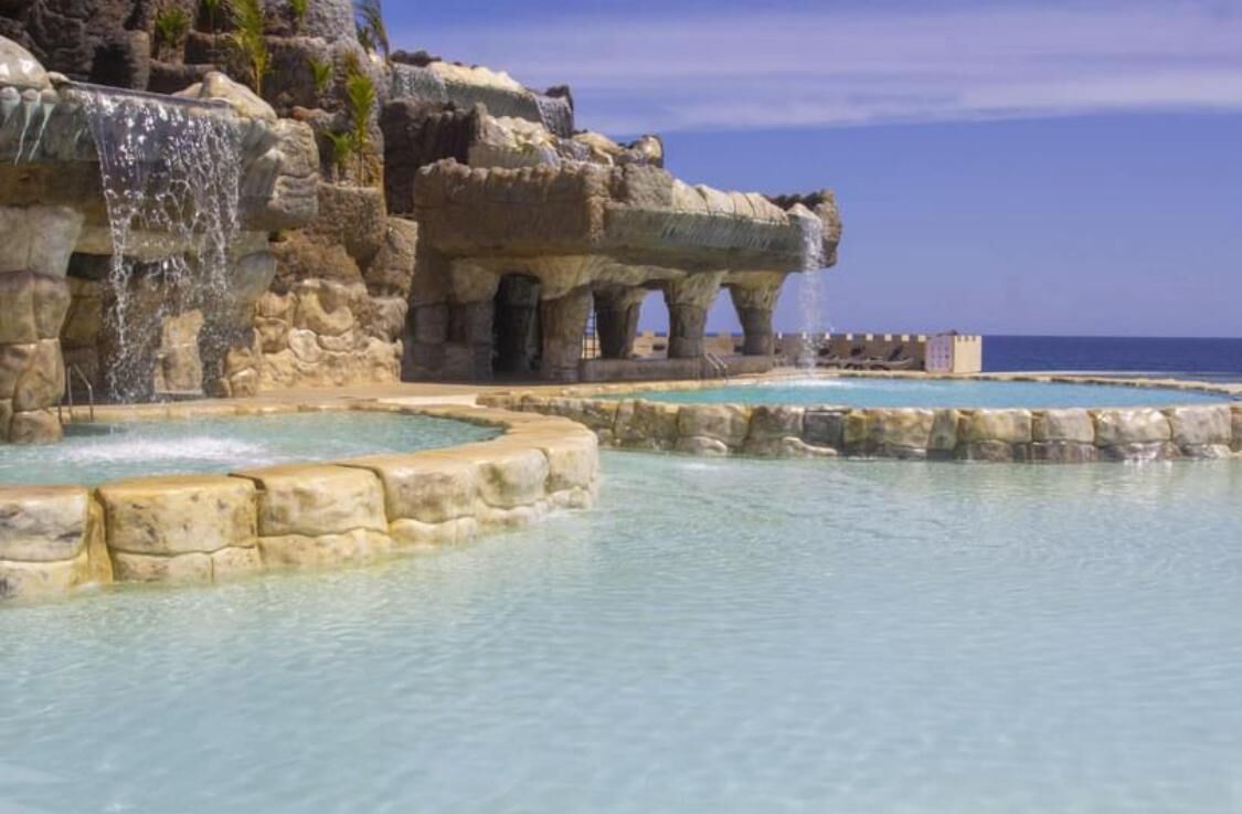 A natural rock formation with a pool and waterfall.