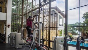 Un gimnasio con equipo de ejercicio y un amplio ventanal con vistas a una piscina.