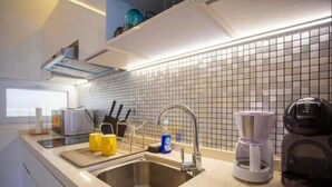 Una cocina moderna con un lavamanos de acero inoxidable, una cafetera y un hervidor.