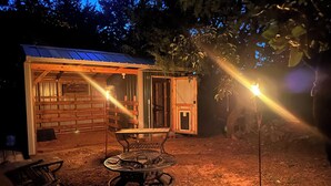 A rustic wooden cabin with a metal roof, a small porch, and a table with chairs.