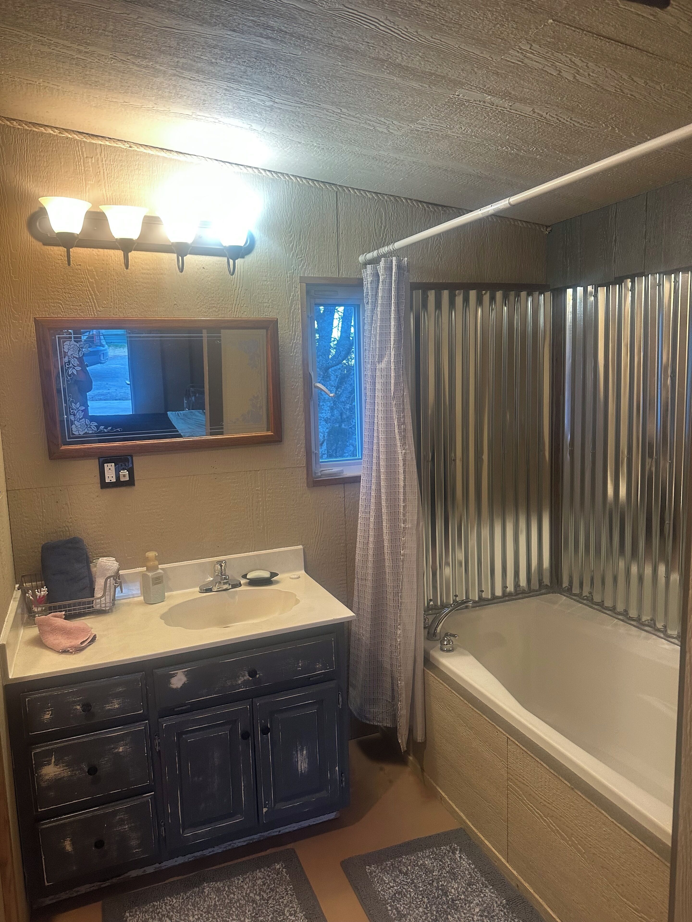 A bathroom with a vanity, a large mirror, a bathtub, and a shower curtain.