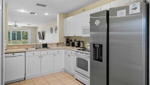 A modern kitchen with white cabinets, stainless steel appliances, a built-in oven, and a water dispenser.
