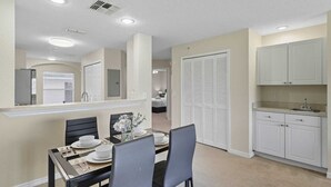 A compact living space with a dining area, kitchenette, and a bedroom visible through an open door.
