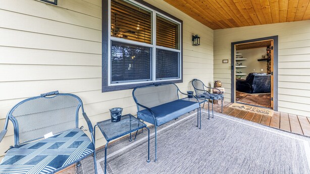 A covered porch with a bench, chairs, and a small table. - Heavenly Pines (Ruidoso)